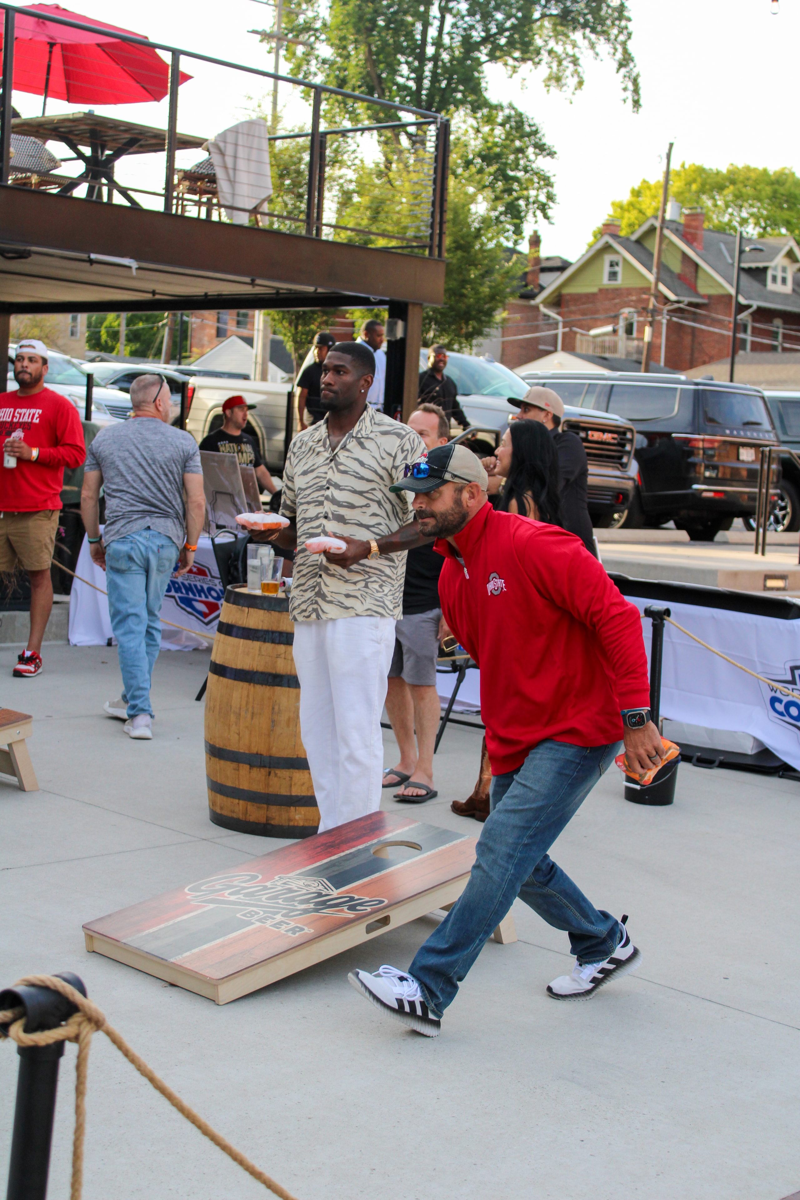 Athlete throwing cornhole bag with Ohio State fan watching