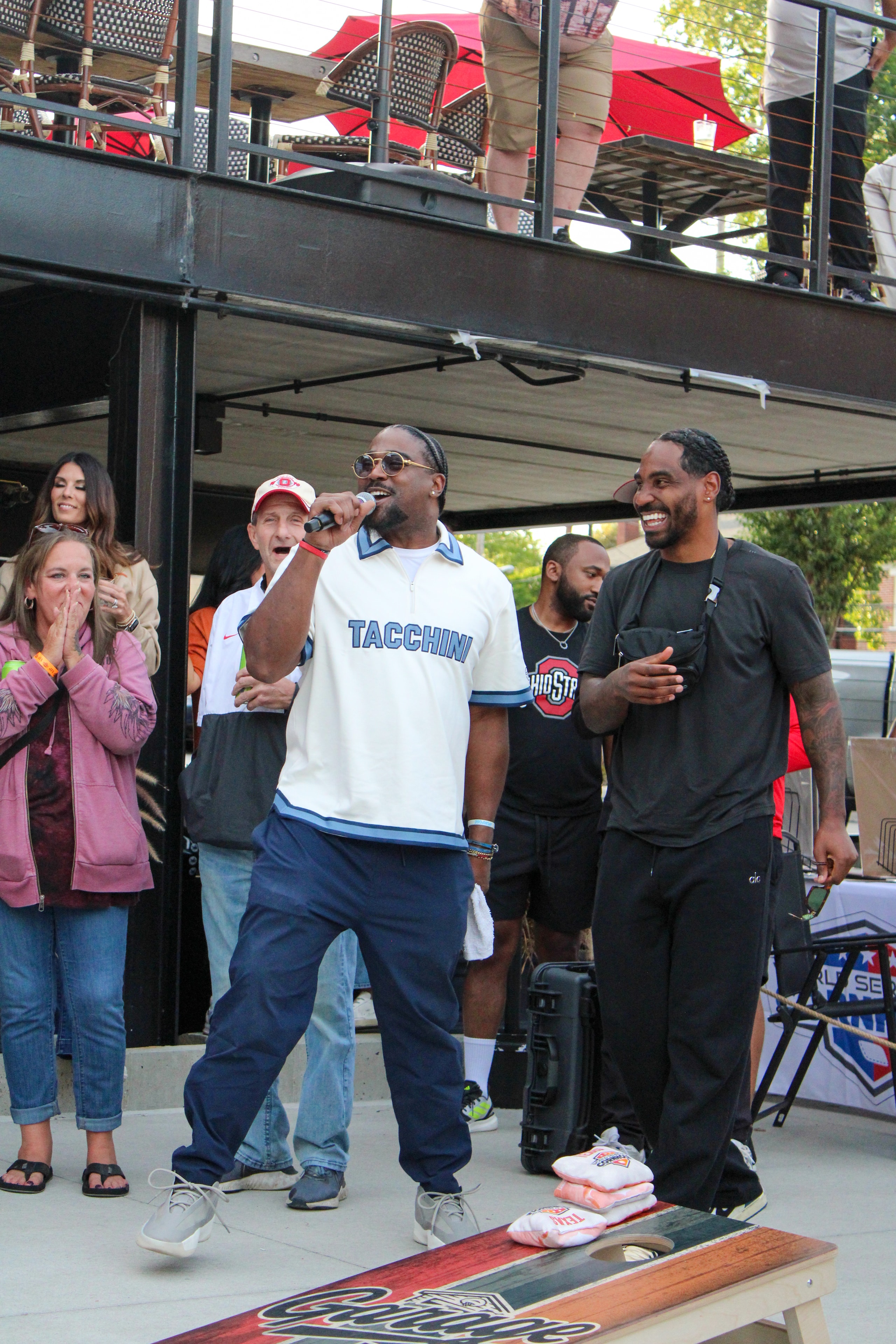 Athletes laughing and celebrating at the cornhole board