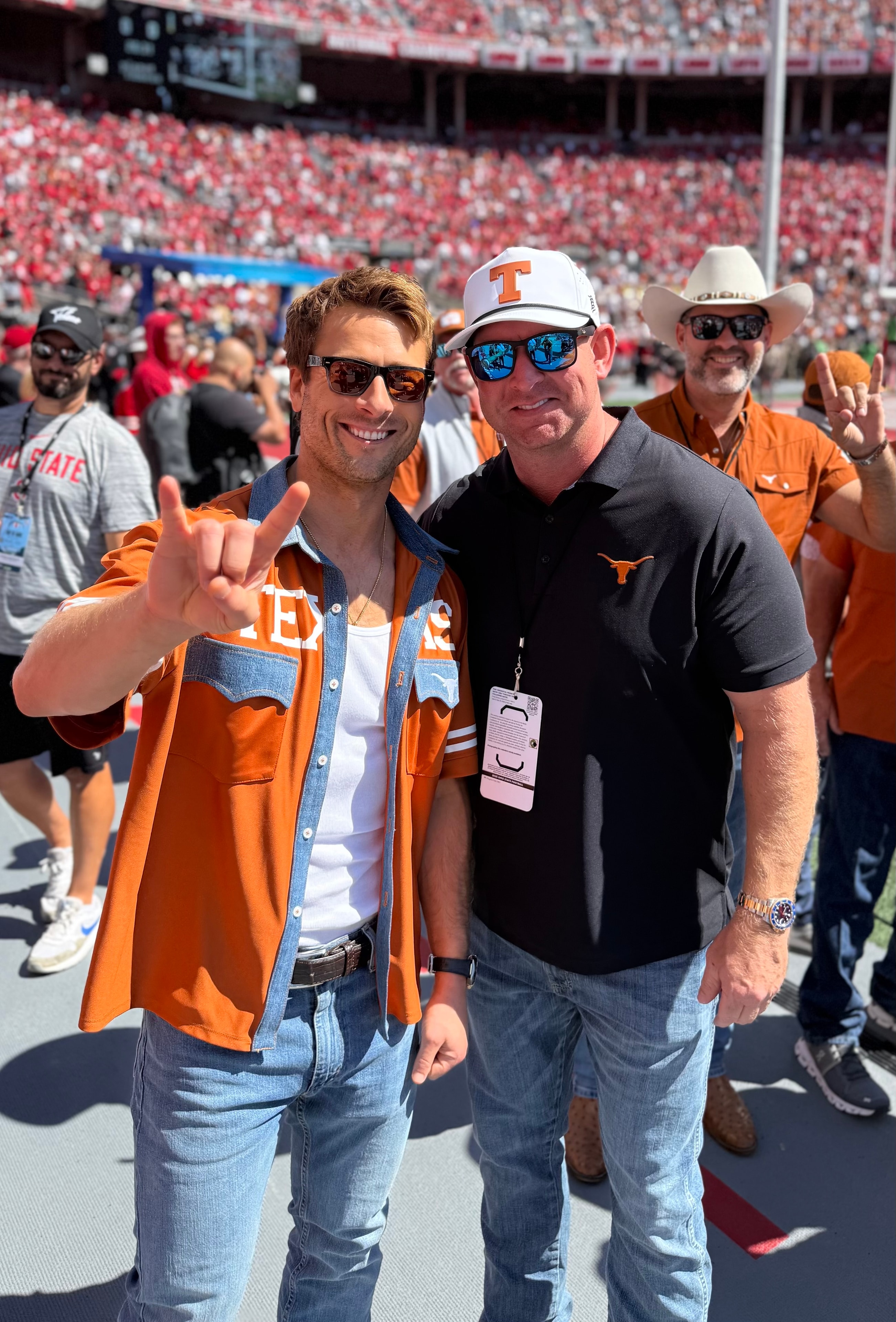 Two Texas fans on the field at Ohio Stadium throwing Hook 'Em horns