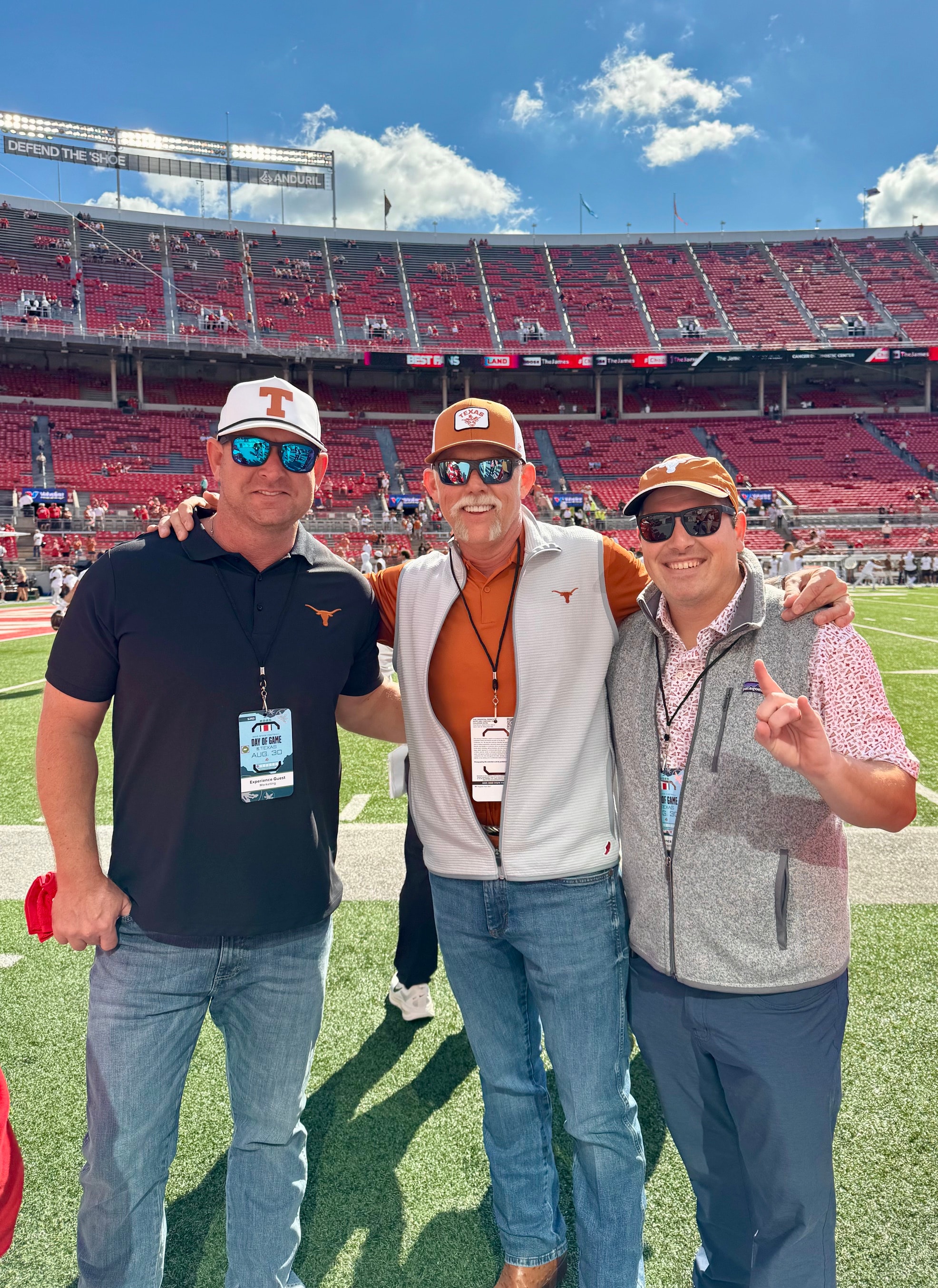Three Texas fans on the field at Ohio Stadium with VIP credentials