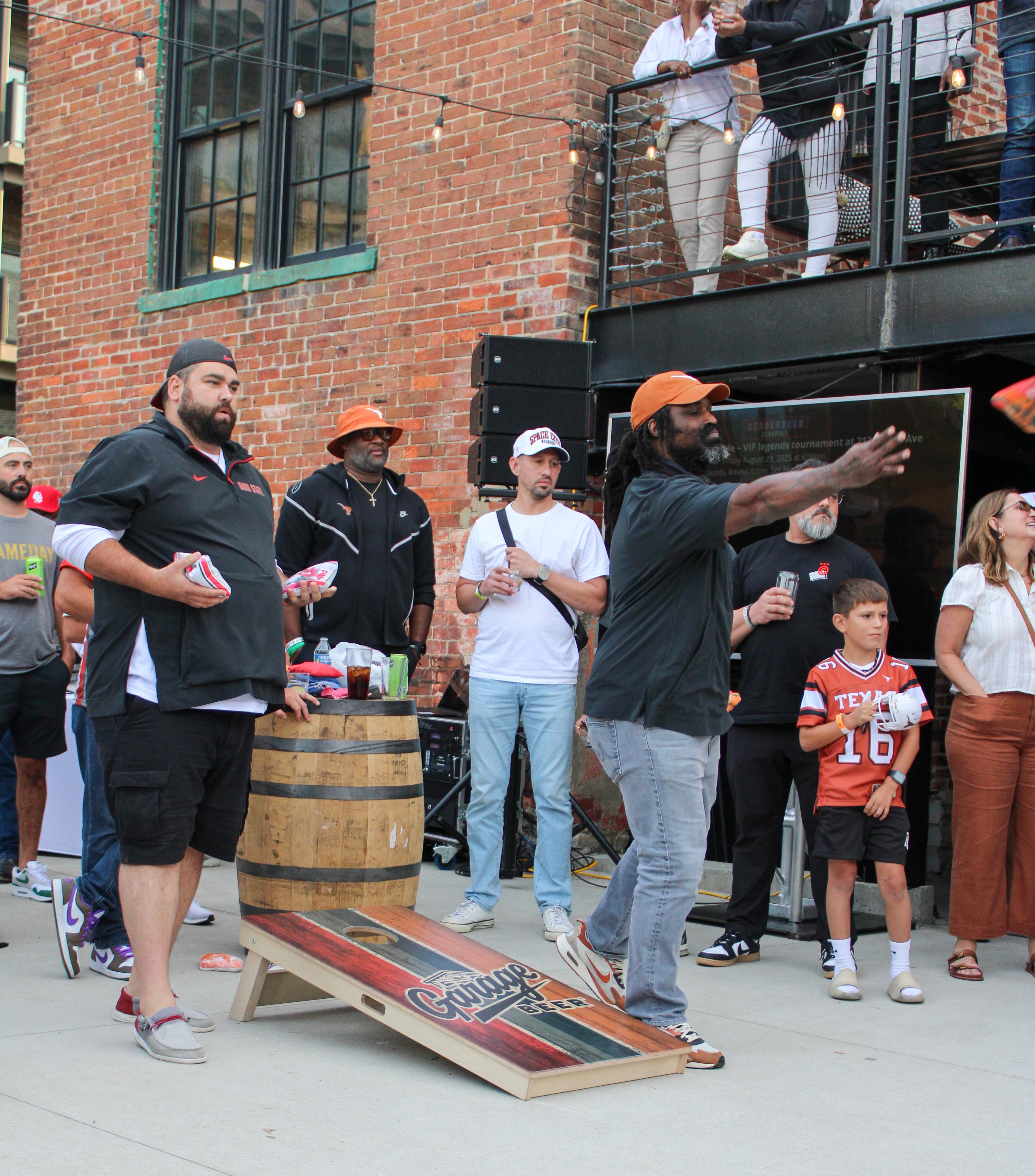 Players throwing cornhole bags with spectators watching